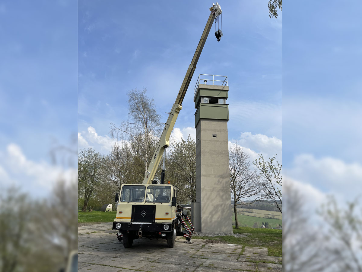 Vollständig aufgebauter Beobachtungsturm in Culitzsch vor grünen Wiesen und blauem Himmel. Daneben Kran mit ausgefahrenem Arm.